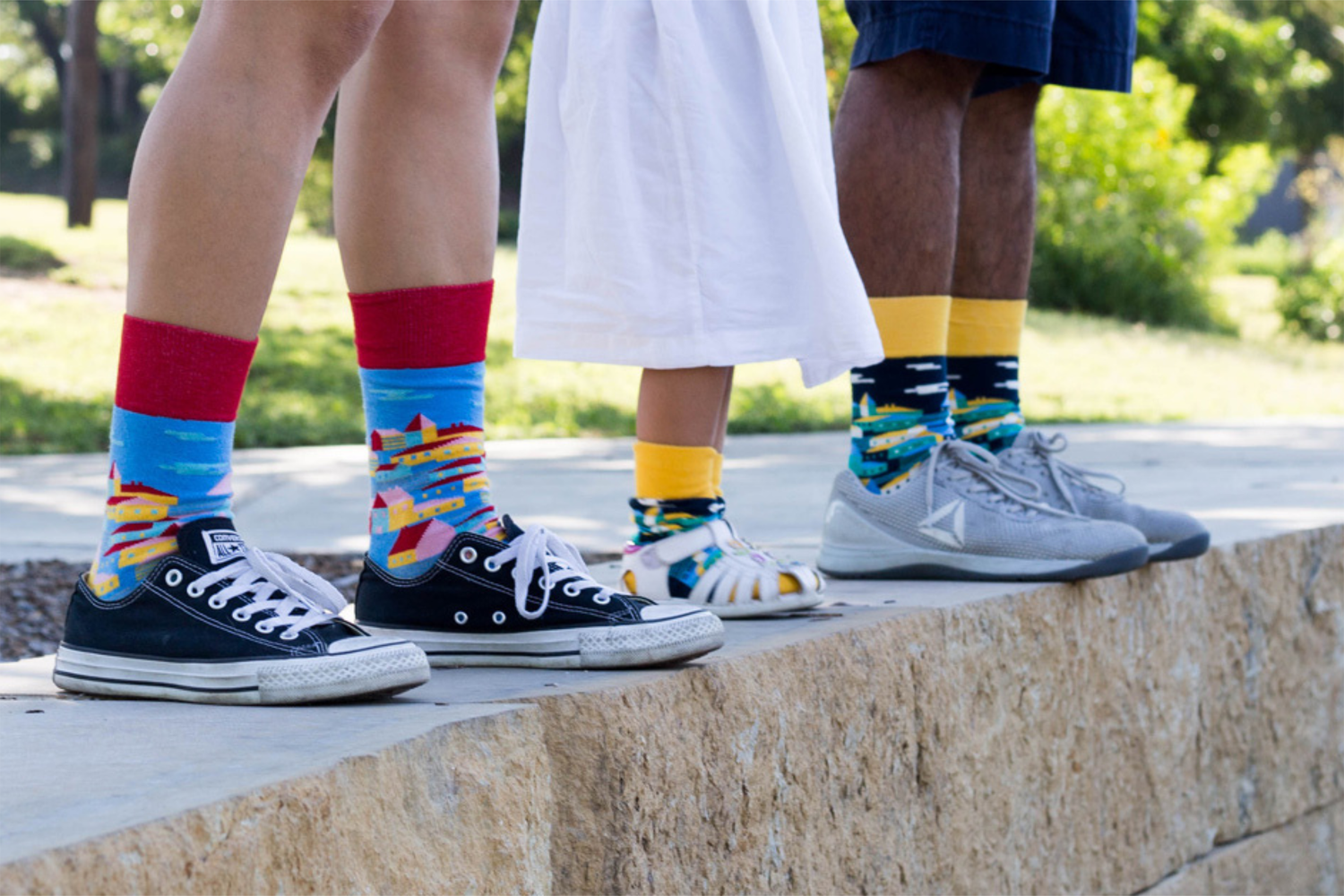 Three people standing on ledge wearing cool socks by Sock Club