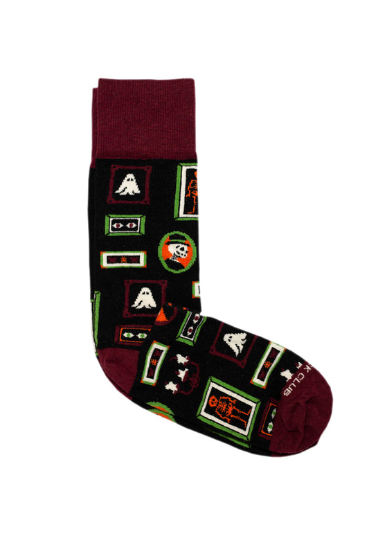 Black sock with maroon heel, toe, and cuff covered in pictures of portraits containing ghosts and skeletons